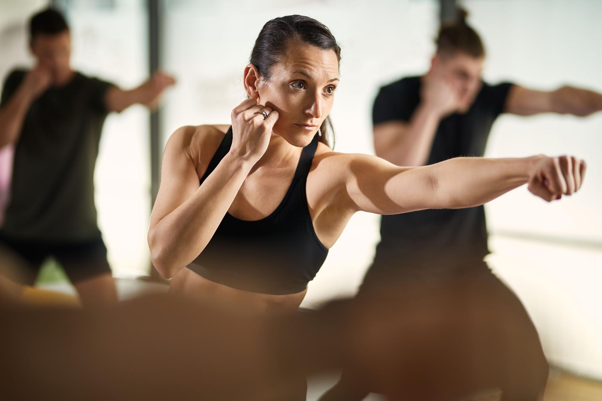 Athletic woman in fighting stance practicing martial arts at health club.