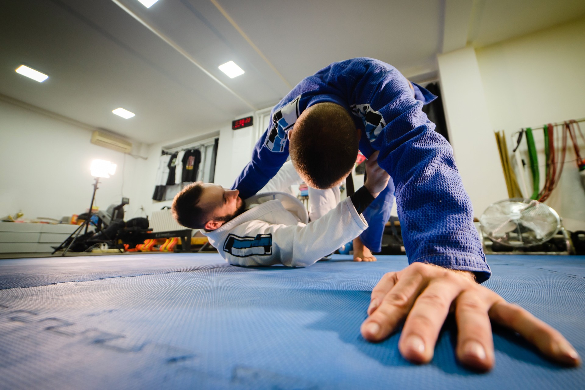 Brazilian jiu jitsu BJJ training sparing two athletes in sweep guard position drilling technique wearing kimono gi